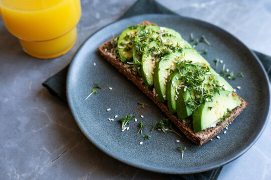 Authentic Scandinavian avocado rye bread sandwich breakfast with orange juice.