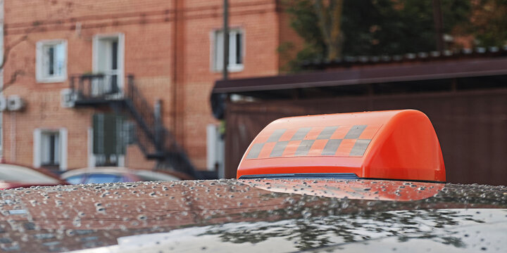 Taxi roof sign displaying a checkerboard pattern on a wet car, reflecting urban setting and public transportation in the city