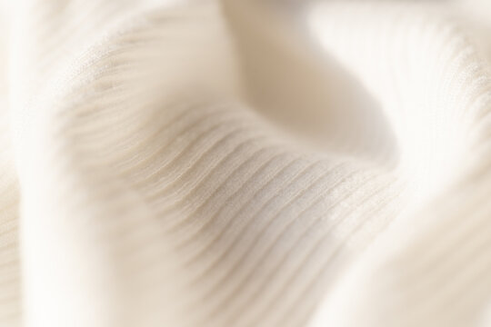 Macro shot of white ribbed knit fabric texture with soft drapery and shadows