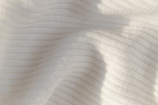 Macro shot of white ribbed knit fabric texture with soft drapery and shadows