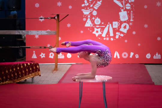 Young contortionist balances on a stage table. Concept: Christmas holiday campaign ads, festive family entertainment, and youth talent promotions