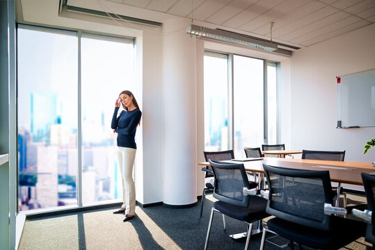 Full length of a confident businesswoman in a modern glass-walled office with cityscape
