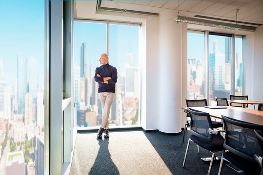 Businessman looking out city from a large window in the office
