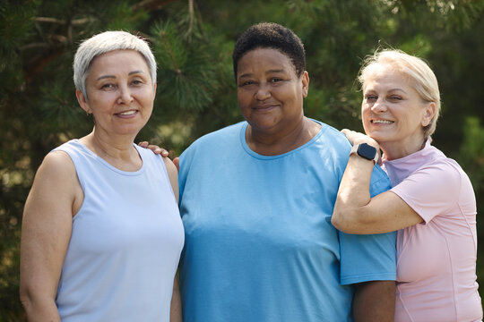 Portrait of diverse group of senior women smiling together in park, representing active aging and social inclusion. Image suitable for healthcare and wellness marketing campaigns