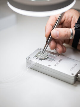 Technician Aligning Fiber Optics in Precision Optical Block with Tweezers