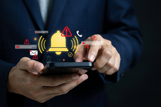 Executive using mobile device to handle critical business notifications with warning symbols holographic icons alert signs urgent digital communication alert message system concept closeup.