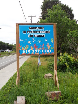 Gatineau, Quebec, Canada &ndash; June 13, 2026: A bright blue "Garderie La Pr&eacute;maternelle Du Village sign" stands outdoors near a roadway on Chem. Eardley.
