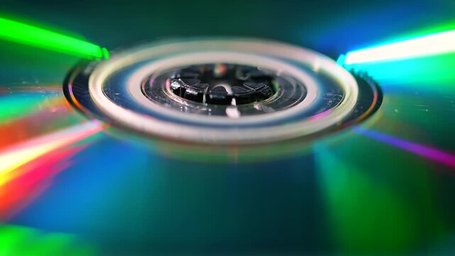 Macro view of a compact disc center reflecting green, blue and red light across its glossy surface. Concept retro technology, data storage, music branding and digital advertising.