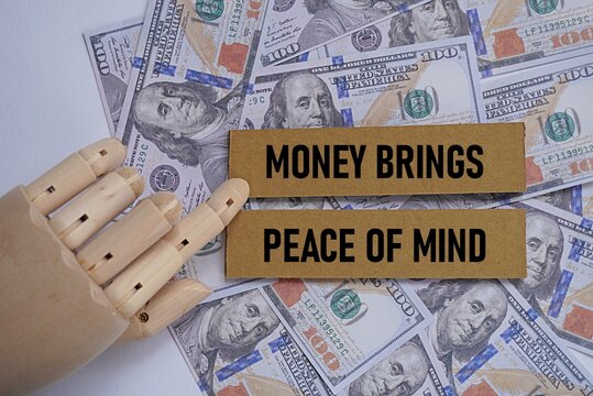 Replica wooden hand holding a printed card MONEY BRINGS PEACE OF MIND. Financial concept. The need and use of money in every activity. Having enough wealth makes life easier