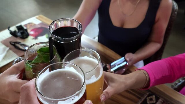 Casual toast with drinks around weathered wooden table among friends under warm ambient lighting, celebrating relaxed social dining mood with mint garnish, frothy glasses and cozy rustic setting