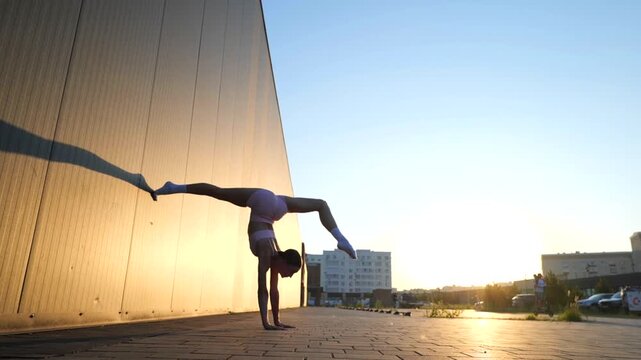 Female Acrobat Practicing Handstand Split Near Modern Building