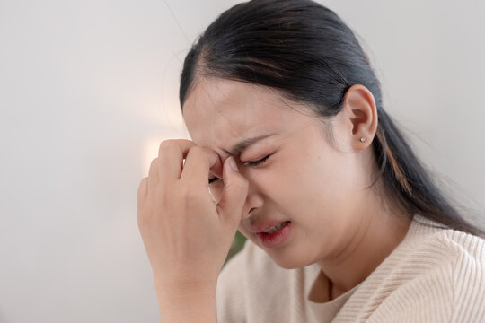 asian woman suffering from severe headache experiencing deep pain and emotional stress while holding hand to face showing sad exhausted painful expression.