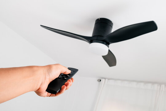 man operating a ceiling fan with remote control