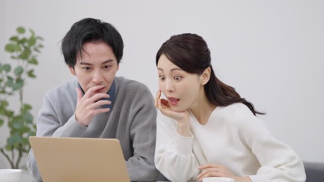 パソコンを見て驚く夫婦・カップル
