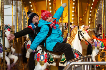 Children enjoy riding a carousel at an amusement park during the winter season in a bright and lively setting © Светлана Лазаренко