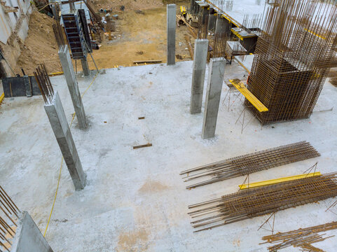 Workers are busy at construction site where concrete columns rebar are being placed for new building foundation.