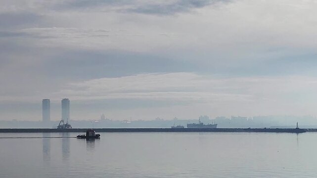 Small ship crossing the river at port of montevideo city during a misty winter morning in Montevideo.