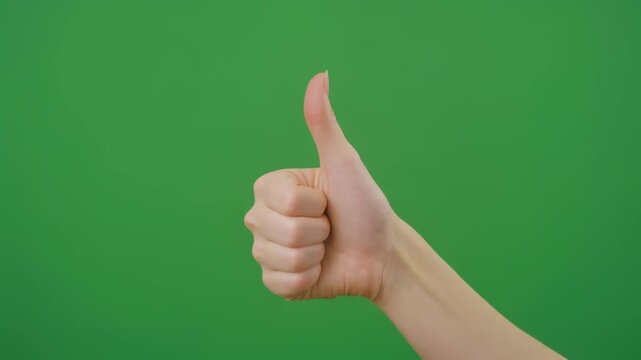 Hand giving positive approval gesture with thumb up on green screen background