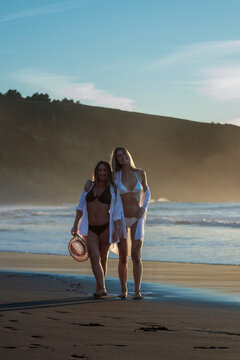 Two women friends enjoying beach vacation at sunset