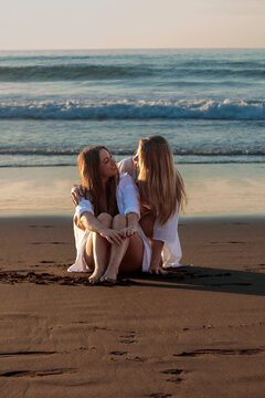 Lesbian couple embracing on beach at sunset