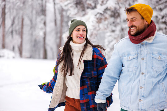 Couple having fun going sliding in the snow in the mountains while on winter vacation
