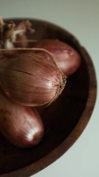 Whole echalion banana shallots with dry, papery peel rests tied together on a white grid-patterned kitchen linen. For cooking shows, culinary blogs, recipe tutorials, organic farming promotions.