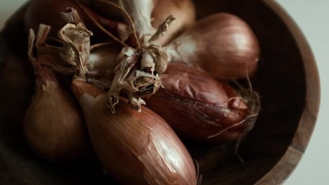 Whole echalion banana shallots with dry, papery peel rests tied together on a white grid-patterned kitchen linen. For cooking shows, culinary blogs, recipe tutorials, organic farming promotions.