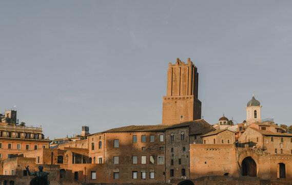 Luz dorada sobre los antiguos muros de ladrillo y la imponente Torre delle Milizie en los foros romanos al atardecer