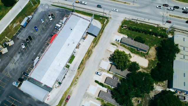 FM 306 traffic corridors run parallel to commercial storefront structures adjacent to residential zones. Drone perspective outlines access routes connecting commercial hubs in New Braunfels, TX