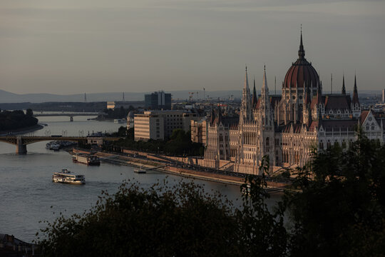Warm evening sunlight illuminates the majestic gothic architecture of the Hungarian Parliament Building along the calm Danube River. Such iconic urban landscapes inspire memorable European travel.