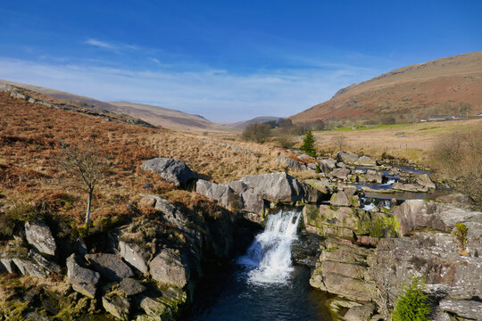 Clear sky above rugged valley with falling waterfall