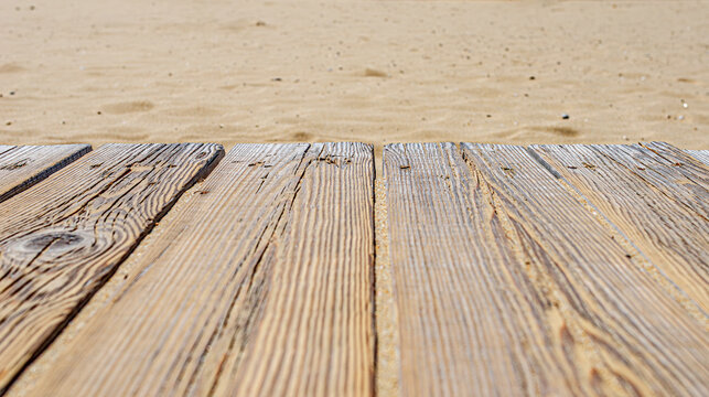 A close-up view of weathered wooden planks lying on a golden sandy beach.