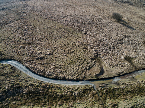 Curving river winds through dry, textured terrain
