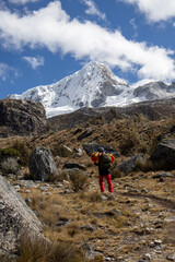 Naklejka premium Mountaineer trekking on a trail towards a massive snowy mountain