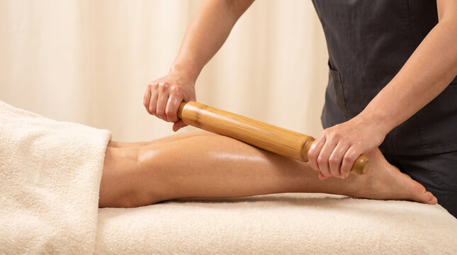 A therapist performing a wood therapy massage on a client's leg using a wooden roller tool, ad social media download thambnail poster web template event festival 2026 2027 2028