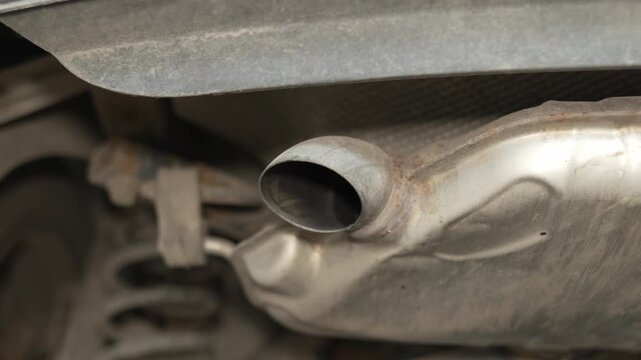 A metal car muffler exhaust pipe tailpipe under the vehicle.