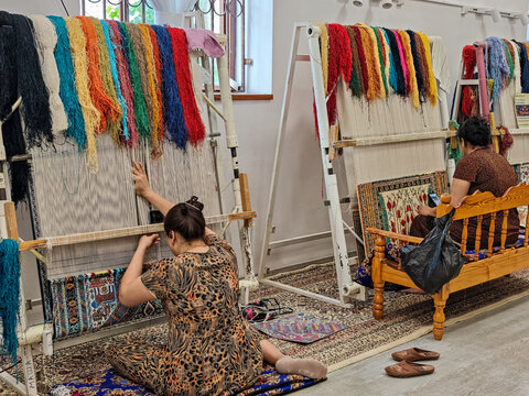 Women weaving a silk carpet on a factory of Bukhara on Uzbekistan