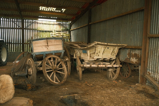 Weathered carts rest inside a rustic barn