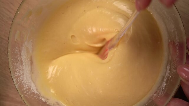 The process of preparing a liquid dough from eggs and flour, women's hands pour the ingredients into a bowl and then mix everything together