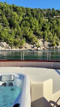 Luxury boutique yacht deck in Croatia with jacuzzi, sea view and pine-covered coastline. Vertical video capturing a premium Mediterranean travel experience and relaxing summer atmosphere.