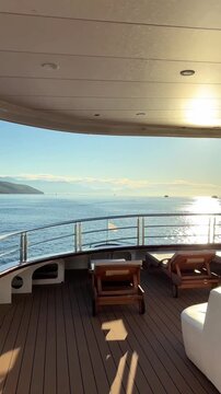Luxury boutique yacht deck with elegant wooden sun loungers, showcasing a premium sailing experience and relaxing Mediterranean lifestyle. Stylish boat interior design, high-end travel. Vertical video