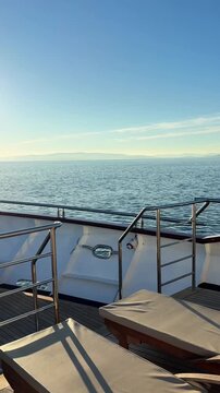 Luxury boutique yacht deck with elegant wooden sun loungers, showcasing a premium sailing experience and relaxing Mediterranean lifestyle. Stylish boat interior design, high-end travel. Vertical video