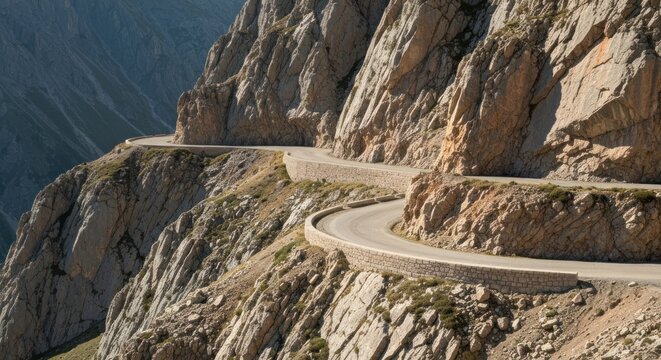 A winding road snakes along a steep mountain cliff side, framed by rocky terrain