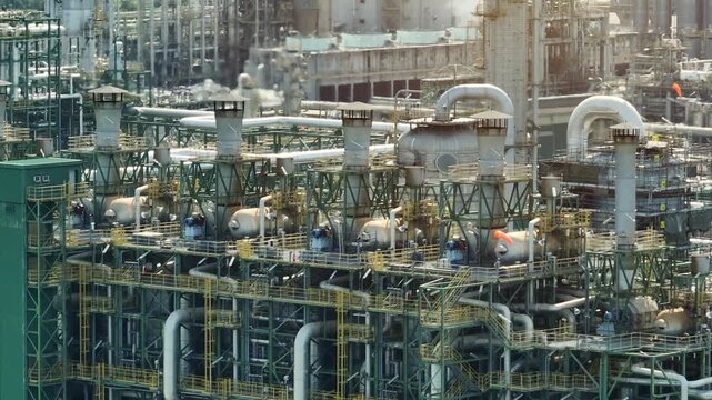 An aerial view of refinery infrastructure with extensive piping networks and chemical processing units, highlighting industrial innovation, operational efficiency, the challenges of energy transition.