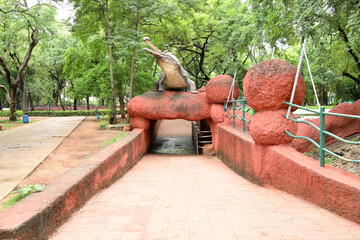 Crocodile themed tunnel entrance in lush tropical park with scenic walking pathway © Pleasant Mode