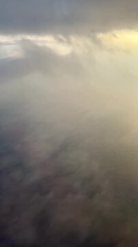 Airplane window view of descent through clouds at sunrise over the Mediterranean Sea