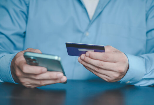 Businessman using smartphone and holding credit card for online payment. Digital fintech, mobile banking, e-commerce transaction, and secure electronic financial service technology concept.