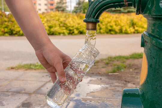 Close-up of a person refilling a reusable glass water bottle from a public drinking fountain outdoors. Sustainable lifestyle, clean drinking water, hydration, refill station and plastic-free living co