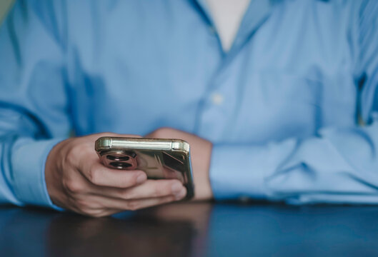 Close up of businessman holding and using smartphone on desk. Concept of digital communication, mobile technology, online business networking, and modern professional wireless lifestyle.