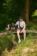 Obraz premium Man and dog resting together on log during peaceful forest hike. Concept of hiking rest break, outdoor pet friendship, slow nature lifestyle.